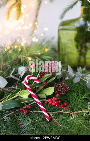 Sfondo verde di foglie viventi e rami, rosso caramella di Natale. La composizione di Capodanno, un'apertura pronta all'uso. Capodanno e festa di Natale Foto Stock