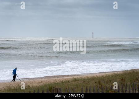 un cacciatore di tesori con metal detector in tempesta sulla spiaggia Foto Stock