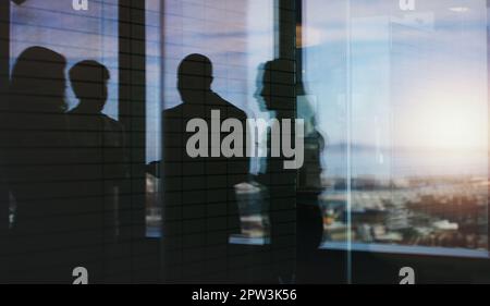 Più grande è il tuo cerchio, maggiore è il tuo successo. Silhouette ripresa di un gruppo di uomini d'affari che hanno una discussione all'interno di un edificio di uffici. Foto Stock