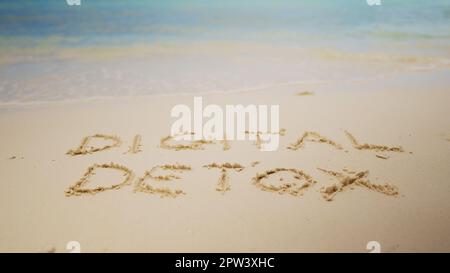 Digital Detox parola scritta sulla sabbia vicino al mare in spiaggia Foto Stock