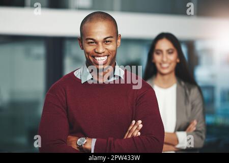 Youll andare lontano finchè avete fiducia. Ritratto di un giovane uomo d'affari in un ufficio con il suo collega sullo sfondo. Foto Stock