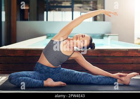 Perfezionare le sue pose yoga. una bella giovane donna che pratica yoga fuori. Foto Stock