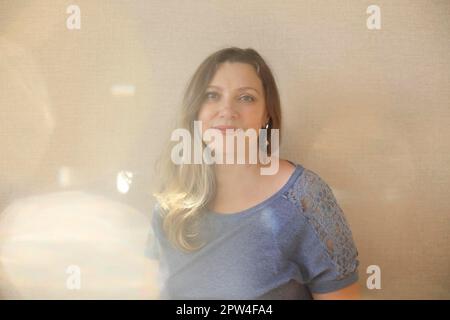 Amatevi ad ogni età. Donna di mezza età 50s che guarda la macchina fotografica mentre posa isolata su sfondo beige chiaro, sentendosi bella e giovane. Foto Stock