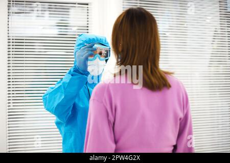 Operatrice medica in dispositivi di protezione individuale DPI che esegue il test PCR a una paziente in gravidanza in laboratorio medico, infermiere test in attesa madre Foto Stock