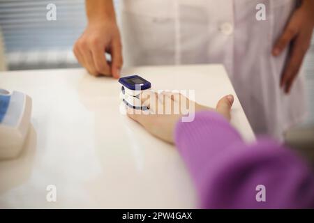 Donna in gravidanza con pulsossimetro sul dito. Medico che misura il livello di saturazione di ossigeno mentre la madre in attesa visita con la malattia di coronavirus a. Foto Stock