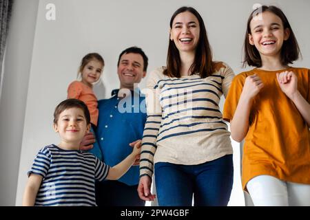 Bambini eccitati che arrivano a casa con i loro genitori. I bambini tornano a casa con i genitori mamma e papà, sorridendo carini figli fratello e sorelle, entrando Foto Stock