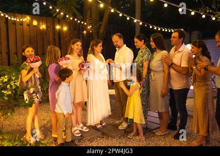 Cerimonia di matrimonio aperta. Sposa, sposo, uomo migliore, le bridesmaids intorno. Celebrazione del matrimonio all'aperto. Bouquet di fiori, anelli, voti. Amici felici. Foto Stock