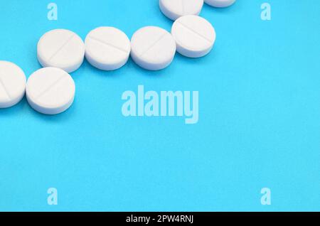 Un paio di compresse bianche giacciono su un blu brillante superficie di sfondo. Immagine di sfondo sul farmaceutico e medico, argomenti Foto Stock