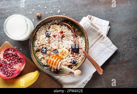 Una ciotola di muesli servita con frutta fresca e miele. Piatto di farina d'avena. Cibo sano, dieta. Vista dall'alto. Foto Stock