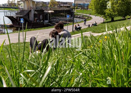 Cracovia, Polonia. 28th Apr, 2023. La gente riposa lungo un fiume Vistola nella città vecchia di Cracovia come erba circostante è permesso di crescere senza tagli frequenti. Una famosa città turistica in Polonia, ha deciso di limitare il taglio di erba spazio pubblico. Lasciare crescere l'erba aiuterà l'ambiente, rinfrescherà la città nel cambiamento climatico e incoraggerà la biodiversità. (Credit Image: © Dominika Zarzycka/SOPA Images via ZUMA Press Wire) SOLO PER USO EDITORIALE! Non per USO commerciale! Credit: ZUMA Press, Inc./Alamy Live News Foto Stock