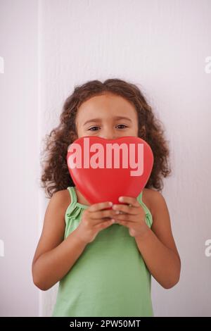 Se vi do il mio cuore per favore non romperlo. una giovane ragazza sorridente mentre tiene un giocattolo a forma di cuore Foto Stock