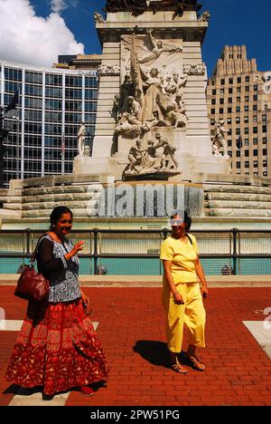 Una famiglia, che indossa abiti tradizionali, gode di una giornata di sole passeggiando intorno al monumento ai marinai e ai soldati di Indianapolis Foto Stock