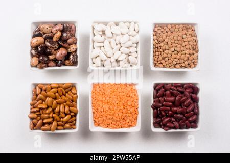 Ingredienti alimentari diversi dalla famiglia dei legumi come fagioli e lenticchie su sfondo bianco. Foto Stock