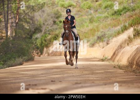 Vivere la natura a cavallo. Una giovane donna che va per un giro sul suo cavallo di castagno Foto Stock