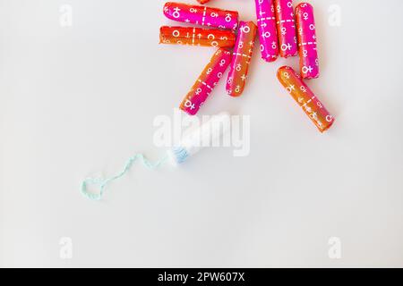 Tampone medico femminile in confezione rosa e arancione su sfondo bianco. Tampone igienico bianco per le donne. Bastoncino di cotone. Mestruazioni, contraccezione Foto Stock