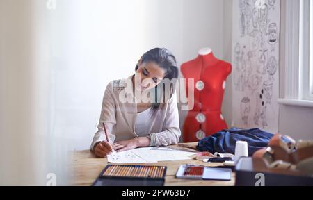 Creare questa stagione tendenze. Un giovane stilista di moda che fa schizzi nel suo ufficio Foto Stock