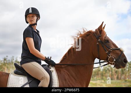 Vivere la natura a cavallo. Una giovane donna che va per un giro sul suo cavallo di castagno Foto Stock