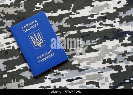 Passaporto straniero ucraino su tessuto con tessuto di camouflage pixed militare. Panno con motivo camo in pixel grigio, marrone e verde e Regno Unito Foto Stock