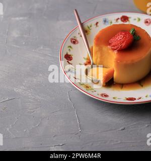 Pudding Caramel Custard con fragola su sfondo cemento, Copy Space for Text Foto Stock