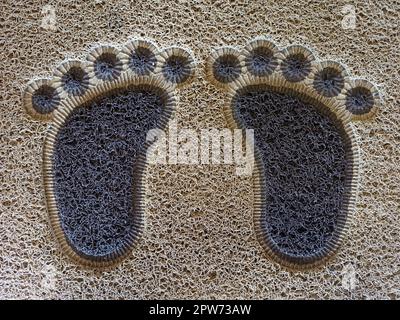 Tappeto di stoffa di fronte all'ingresso della casa. Tappetino. Tappeto con piedi divertenti. Tappeto davanti alle porte d'ingresso dell'appartamento. Piedi con le dita dei piedi. Foto Stock