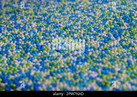 Immagine di sfondo di una varietà di vetri colorati in polvere in forma di piccole sfere. Un numero enorme di dolce, perline colorate di dimensione molto piccola per dec Foto Stock