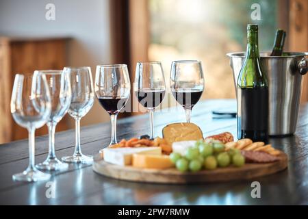 Una fila di bicchieri e un tabellone di formaggi allestiti per una degustazione di vini all'interno di un ristorante. Un piatto di formaggi il vino giusto è l'abbinamento perfetto per un relax Foto Stock
