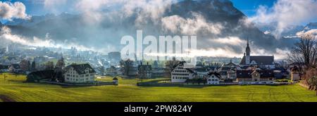 Mattina foschia o sera foschia con i raggi luminosi del sole che la penetrano nella città di Schwyz in Svizzera Foto Stock