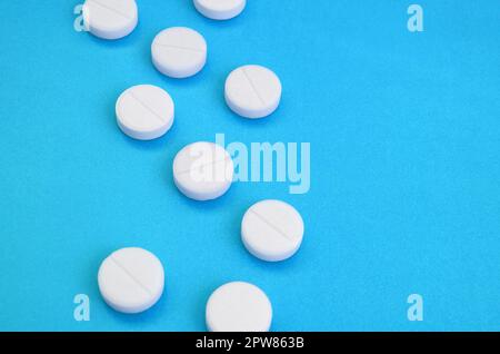Un paio di compresse bianche giacciono su un blu brillante superficie di sfondo. Immagine di sfondo sul farmaceutico e medico, argomenti Foto Stock