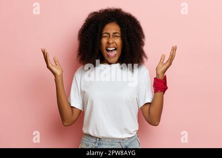 ritratto di una ragazza urlante, ha alzato le mani al suo volto e urla con tutta la sua potenza con la bocca aperta. Foto di alta qualità Foto Stock