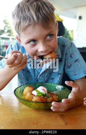 I bambini mangiano banane fritte in pastella nel ristorante Foto Stock
