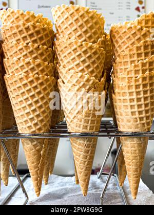 Un mucchio di cialda coni per gelato pronto per essere riempito con gelato in un bar e il ristorante. Vetrina di un bar, una pasticceria e un ristorante . Foto Stock