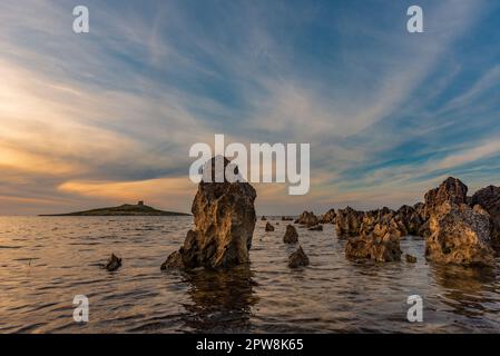 Il sole tramonta dietro l'isolotto di Isola delle femmine, in Sicilia Foto Stock