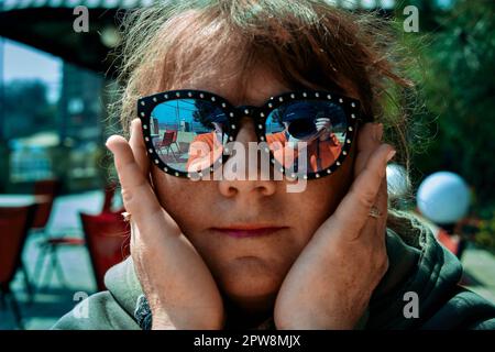 Donna adulta matura in occhiali da sole e un fotografo che riflette in loro in Odessa Ucraina sulla riva del mare Foto Stock