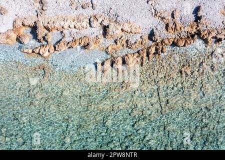 Vista aerea del drone di formazione rocciosa in sfondo di acqua di mare trasparente turchese calmo. Spiaggia greca con grande roccia marrone e pietra grigia, giorno di sole. Foto Stock