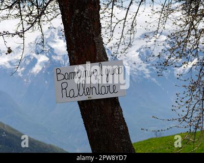 Segnaletica stradale nella città alpina di Lignan che invita i conducenti a rallentare mentre i bambini giocano. Aosta Vally, NW Italia Foto Stock