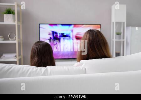 Sorridente madre e figlia guardando la televisione a casa Foto Stock
