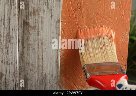 Lavoratore che applica vernice di corallo su superficie di legno, primo piano. Spazio per il testo Foto Stock