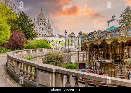 Carosello e giardini formali sotto il Sacré-Cœur a Parigi, che creano un'attrazione familiare colorata nella storica Montmartre. Foto Stock