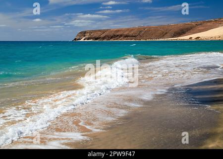 La splendida costa con acqua blu turchese, spiagge luminose e spruzzi d'acqua alla spiaggia Risco del Paso, a est di Fuerteventura, Isole Canarie, Spa Foto Stock