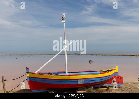 La barca a vela colorata fronteggia il mare rosa a le Salin de Gruissan nel dipartimento dell'Aude Foto Stock