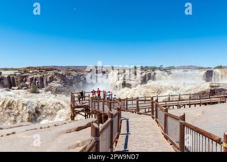 Augrabies National Park, Sudafrica - 25 febbraio 2023: Turisti in un punto di vista presso la cascata principale Augrabies nel fiume Orange. Il fiume è in Flo Foto Stock