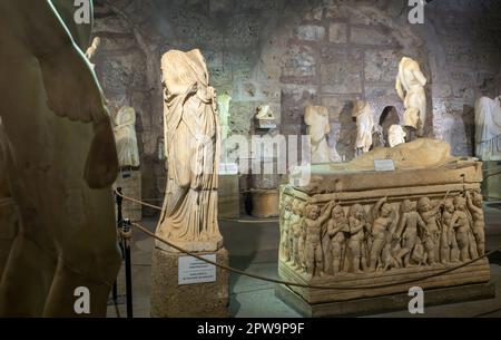 Varie statue romane in marmo e una bara in pietra sarcofago in marmo ornata da un elaborato fregio all'interno del Museo Side, Provincia di Antalya, Turchia (Turco Foto Stock