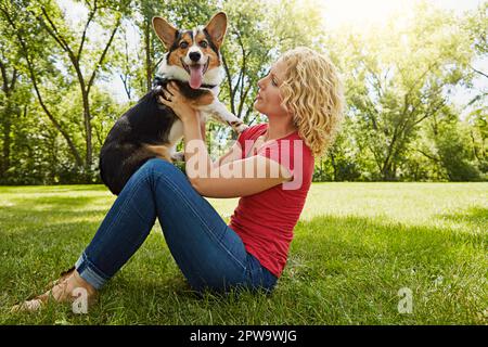 Far sapere al suo cane quanto lo ama. una giovane donna che si lega al suo cane nel parco. Foto Stock