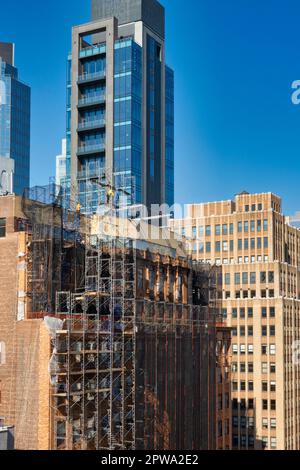 I lavoratori che costruiscono ponteggi di puntamento in un edificio di uffici sulla 34th St. A Midtown Manhattan, 2023, New York City, USA Foto Stock