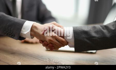 Uomo che scuote le mani con un collega alla scrivania dell'ufficio Foto Stock