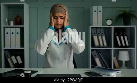 Malata donna musulmana araba sovraccarica medico lavoratore stanco medico medico medico medico soffre di mal di testa toccare la testa ruba templi sensazione di malessere dolore cronico Foto Stock