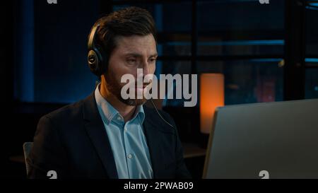 Uomo d'affari manager in cuffie utilizzare il computer auricolare in call center helpline società uomo caucasico 40s adulto che parla distante consulenza clienti Foto Stock