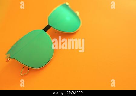Occhiali da sole verdi su sfondo arancione. Spazio di copia Foto Stock