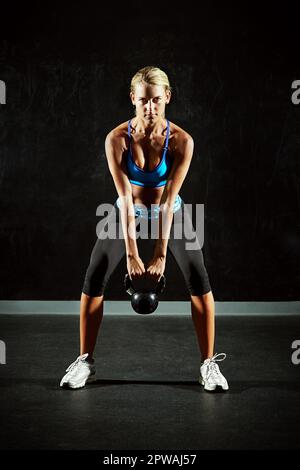 È un buon giorno per sollevare qualcosa di pesante. una giovane donna che fa squats kettlebell in una palestra. Foto Stock