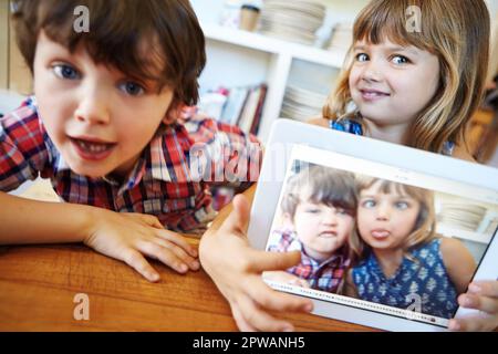 E thats come prendete un selfie. un giovane fratello e una sorella che ti mostrano il loro selfie su un tablet digitale. Foto Stock